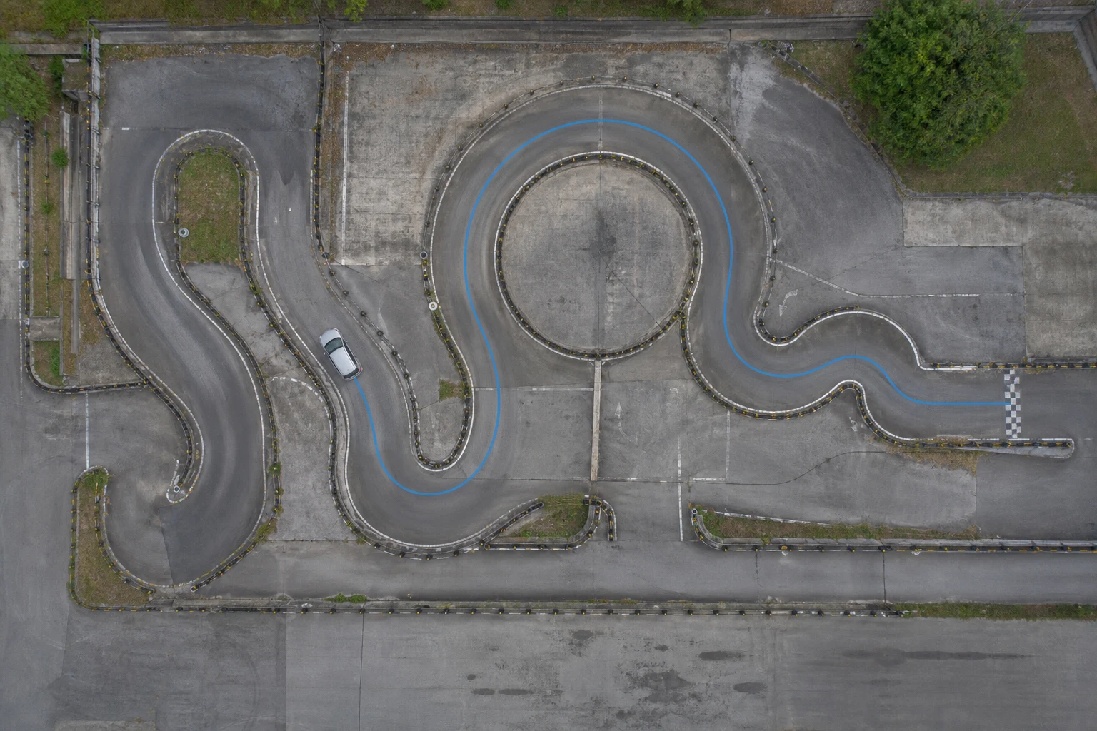 Top-down view of a training car following a curved driving course with a circular loop and finish line
